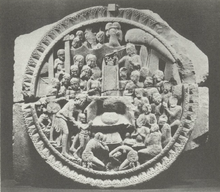 Stone relief with throne at the center and numerous figures surrounding the throne, including a mother and her child