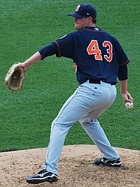 A man in a navy blue baseball uniform with "43" on the back rears back to deliver a pitch.