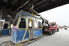 Tollbooth is removed by a large vehicle using straps