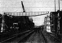 Construction of a bridge with wooden trestles and a long metal span over a railway line