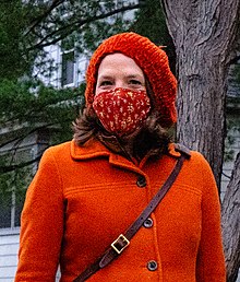 Knuth at bust length, wearing an orange jacket, mask, and hat
