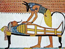 Painting of a jackal-headed god bending over a mummy on a bier