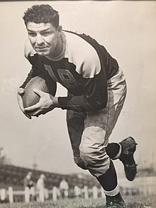 Black and white photo of Falkenstein running the football