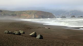 Mori Point is a prominent bluff extending into the Pacific Ocean, seen from a viewpoint looking south from Pacifica Beach.