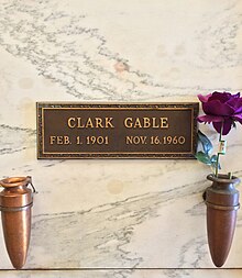 Marble crypt with brass plaque inscribed: Clark Gable, Feb. 1. 1901 Nov. 16. 1960. Two vases are attached to the crypt, one contains a purple rose.