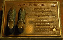 Bronzed shoes on a plaque with text describing Bird's basketball accomplishments