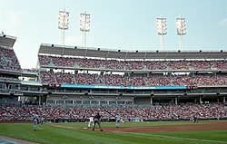 A baseball stadium with blue seats and buildings visible in the background.