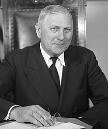 A black and white photograph of a white man in a suit