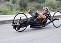 A recumbent racing handcycle with a streamlined frame and thin road racing wheels.