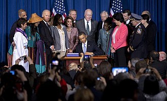 Photograph of Barack Obama signing the VAWA reauthorization, surrounded by numerous major players, including Deborah Parker