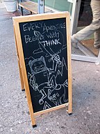 A sandwichboard with a drawing of Finn and Jake, and the caption "Every Adventure Begins With THINK"