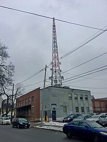 A two-story brick building with a partially dismantled tower behind it