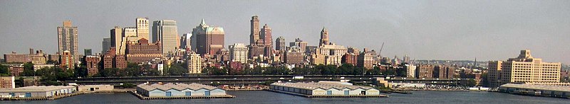 Downtown Brooklyn's skyline consisting of high-rise buildings, and docks in the foreground, viewed from across the East River from Lower Manhattan