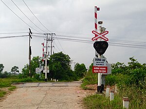 A level crossing at Hanoi, Vietnam, with crossing lights, electric bells, and half-barrier gates in their open position