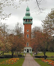 A red brick tower surrounded by trees and topped with a aged copper observation deck