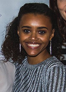A 31-year-old woman with curly brown hair smiling at the camera.