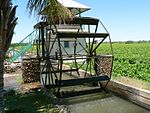 The wrought iron wheel is mounted on the water furrow and shifted by means of reels into the water. Type of site: Bakkiespomp Current use: Agricultural : Water Wheel. This historic water-wheel is one of the few of its kind remaining in South Africa.