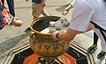 A Thai student pouring the holy water on his two hands at Erawan shrine