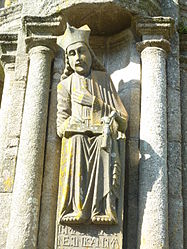 Statue of John the Evangelist outside the south porch of the church of Notre- Dame at Saint-Thégonnec. His attribute the eagle is featured just under his left arm