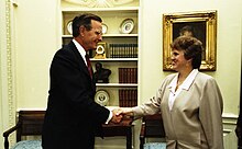 A man and a woman in official suits shaking hands