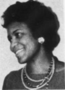 A smiling Black woman wearing several necklaces