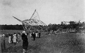 A photograph showing the wreckage of R101 in the background with a number of onlookers to the left of the image