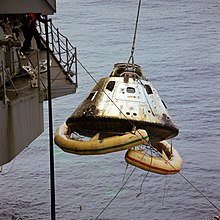 A spacecraft is lifted in the air onto a ship