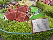 A red-tiled family house miniature with a plaque beside it
