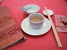 A ceramic spoon in a bowl, pair of chopsticks, plate, and cup of tea