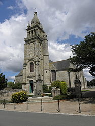 A view of the Église Notre-Dame bell-tower. Note the round tower next to the bell-tower. We can also see the four pinnacles at the top of the bell-tower and the spire. Note the war memorial in front of the building