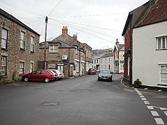 Street scene showing shops and houses with cars.