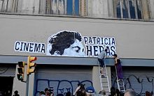 Activists paste up the new name of Cinema Patricia Heras on a squatted cinema
