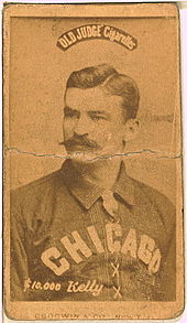 A baseball player is shown sitting, facing slightly left of the camera.
