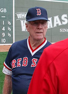 A baseball manager wearing a navy jersey and cap