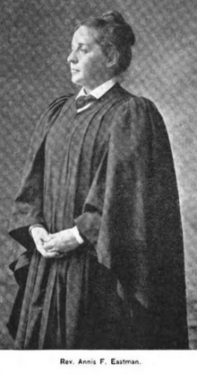 A white woman standing, wearing ministerial robes