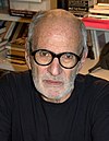 Man in his mid-seventies wearing back circular shaped glasses and sporting greying facial hair