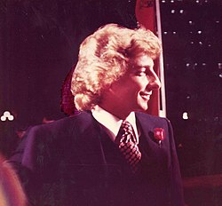A man with long blond hair wearing a jacket and tie