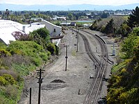 Overview of the former Heathcote station site showing the only remnant of the station still visible, its platform. The Main South Line disappears into the Lyttelton rail tunnel beneath where this picture was taken from.