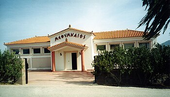 Methymneos winery. Methymneos is spelled in Greek letters above the building's awning-covered, opened door.