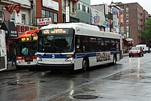 A New Flyer XD40 operating on the Q26 route in downtown Flushing on a cloudy day