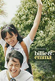 The film poster; against a background of green trees, two girls in catholic school uniforms are riding a bike, which is unseen in the image; Billie - short-haired and grinning, is pedaling and steering, while Emma - who has straight dark shoulder-length hair with a hair bow - is standing behind Billie, and smiling down at her.