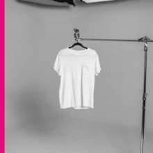A white T-shirt on a coathanger hanging from a metal stand, with a pink line on the left side of the image