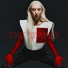 The cover artwork for "The Tower". The cover features Luna in a red and white outfit amongst a grey background. In the middle of the image, the words "The Tower" in red are printed.