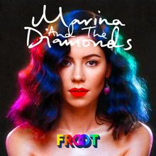 A brunette woman is standing against a black background, with pink and blue neon lighting shining against her hair. Above her, the name "Marina and the Diamonds" is placed, while below her is the title "Froot" in colourful lettering.