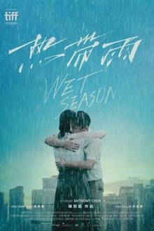 A man and a woman embracing, in the rain, a cityscape in the background