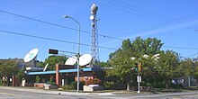 A one-story midcentury building with WFRV-TV signage, satellite dishes on the roof, and a tower with a large radome on top.