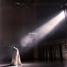 Inside, sunlight from a window high up illuminates a man in flowing religious garb and the word "HUMBLE".
