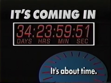 A television screenshot. On a black screen, from top: 1. The words IT'S COMING IN in a bold, white sans serif. 2. Inside a white box, a countdown showing days, hours, minutes and seconds. 3. In the lower right, a blue 3D circle with red elements suggesting the dial faces on a clock and, on top in white, the words "It's about time." in white