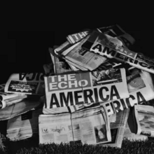 Cover art for "Delresto (Echoes)": a greyscale photo of a pile of newspapers; "The Echo" is the name of the newspaper, and part of the headline reads "America"