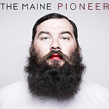 An adult man with a bushy beard, red lips and a white shirt is front-and-centered on the grey cover. The band name appears above the man, along with the album title that's colored twice: one in black and one in red over it.